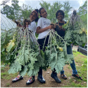 AgriHood Baltimore participants stand with big vegetables