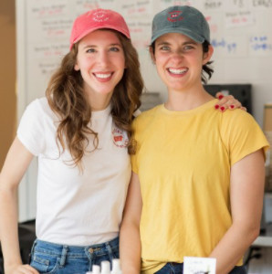 Two women stand smiling in their meat store