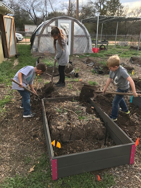 Members of the Menard jr master gardeners club shovel soil into a newly built raised garden bed.