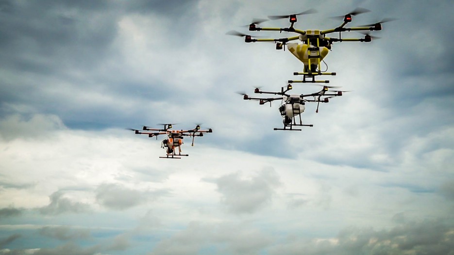 Three drones flying with blue sky and clouds in the background.