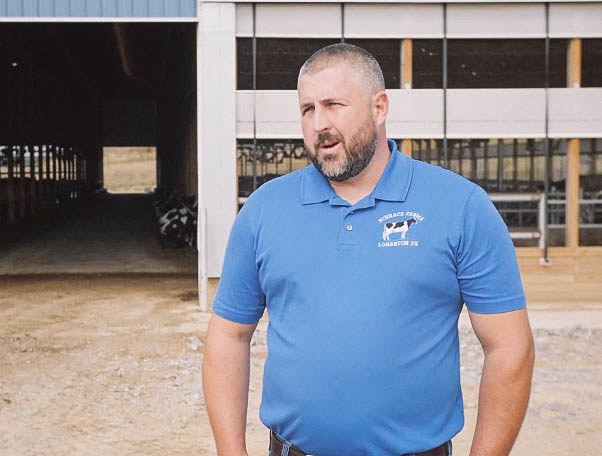 man standing in front of barns witha blue shirt 