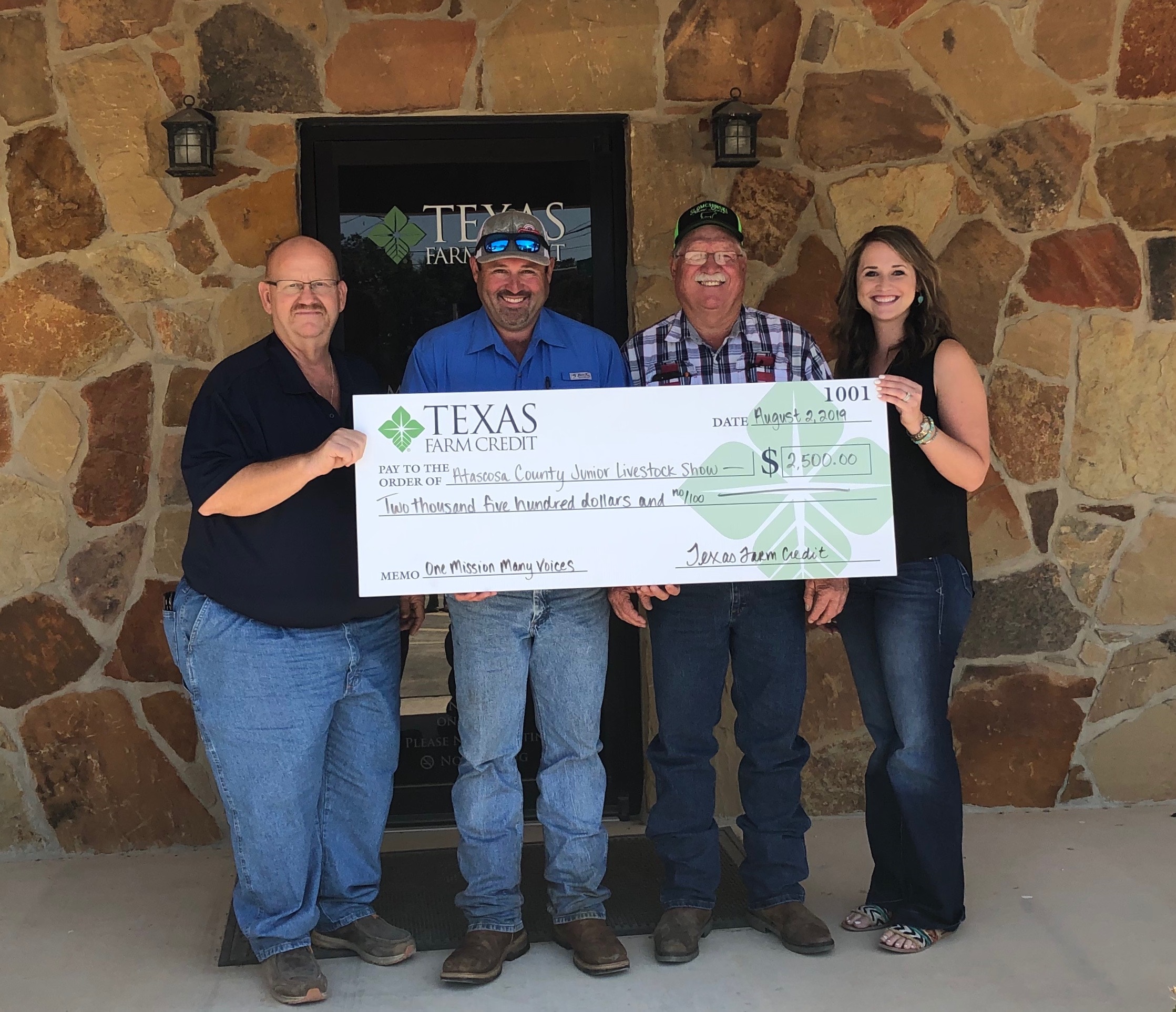 Bill and Brett Slomchinski and Sarah Franklin, their loan officer from Texas Farm Credit, present a check for $2,500 to the Atascosa County Jr Livestock Show.