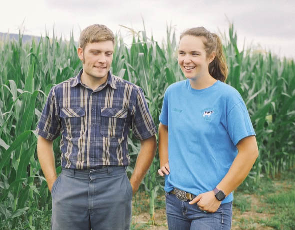 man and woman standing outside in front of corn fields