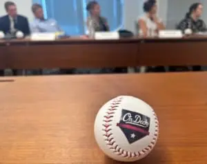baseball in foreground with on deck logo, blurry background of attendees