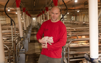 Hog farmer holding piglet